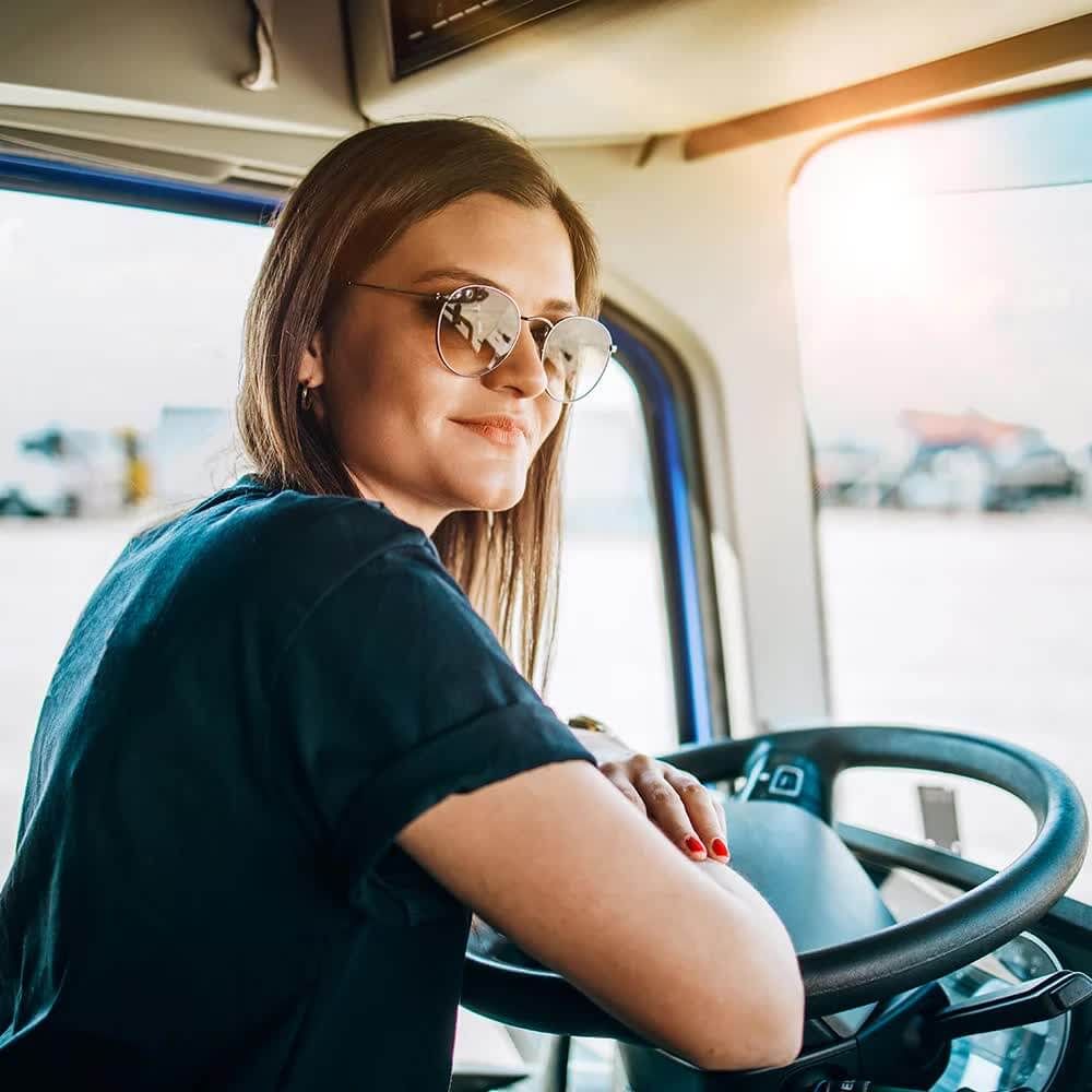 A woman at the wheel of a truck with sunglasses