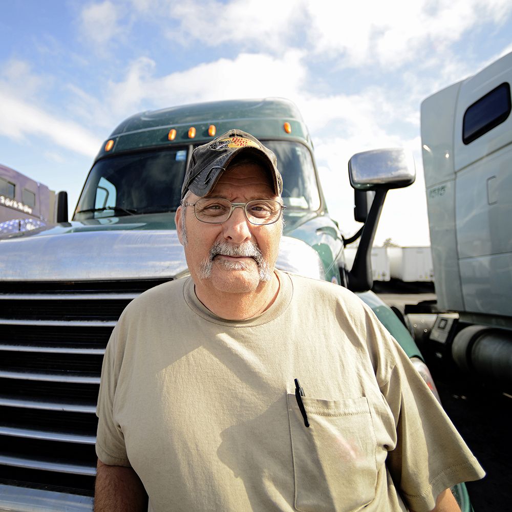 A truck driver in front of a tractor trailer.
