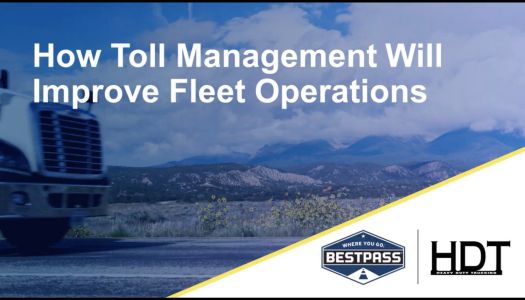The nose/front grates of a white truck are seen, somewhat blurry as if it is speeding down the road. Behind is a gorgeous purple and snow dappled mountain. On the top of the image is white text that reads: "How Toll Management Will Improve Fleet Operations". At the bottom right of the image, a white triangle displays the HDT and Bestpass logos.
